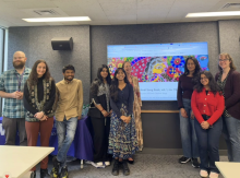 The team behind the Hindi Song Book stands in front of a projector screen showing the project's website