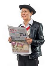 Assunta Ng in a beret holding a newspaper. 