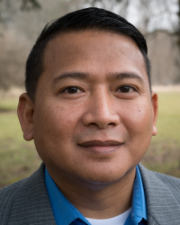 An image of Dr. Nielson Hul, standing against a backdrop of grass and trees