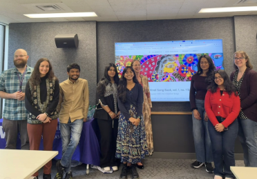 The team behind the Hindi Song Book stands in front of a projector screen showing the project's website