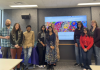 The team behind the Hindi Song Book stands in front of a projector screen showing the project's website